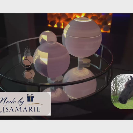 A video featuring three different sized illuminated lithophane globes and a keychain revolving on a table. The Made By LisaMarie logo is displayed in the corner of the video. Soft piano music plays in the background, enhancing the elegant display.